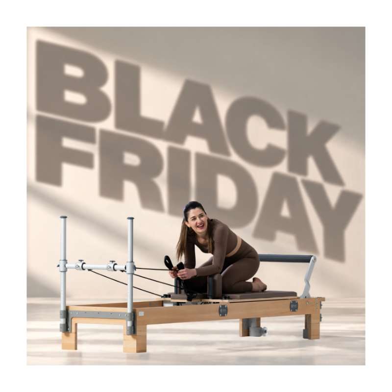 A woman in a brown activewear set kneels on a wooden Pilates reformer machine in a studio, with a large 'BLACK FRIDAY' text overlay in the background.